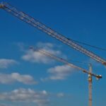 Twee torenkranen met elektrische aandrijving tegen een heldere blauwe lucht, symbool voor duurzaam bouwen
