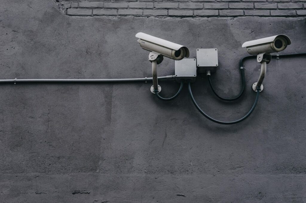Twee beveiligingscamera’s gemonteerd op een grijze muur, essentieel voor zorgbeveiliging en incidentregistratie