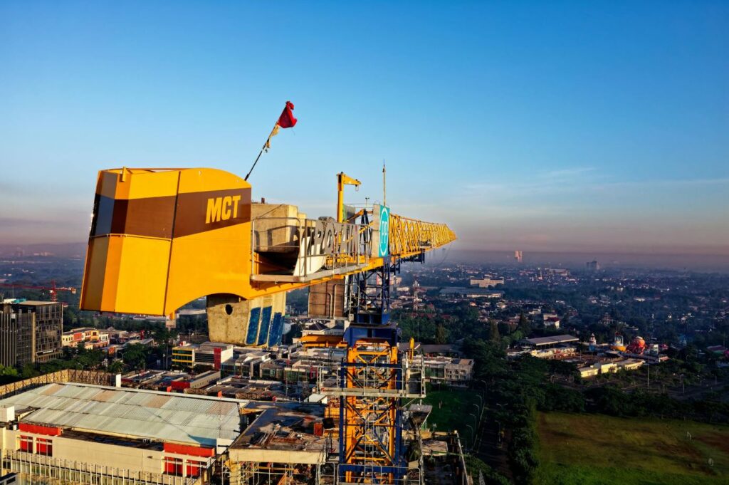 Elektrische bouwkraan op hoogte met uitzicht over stedelijk gebied, bij zonsopkomst in een emissievrije bouwzone