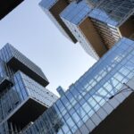 Moderne kantoorgebouwen met glazen vliesgevels en uitstekende volumes tegen een blauwe lucht