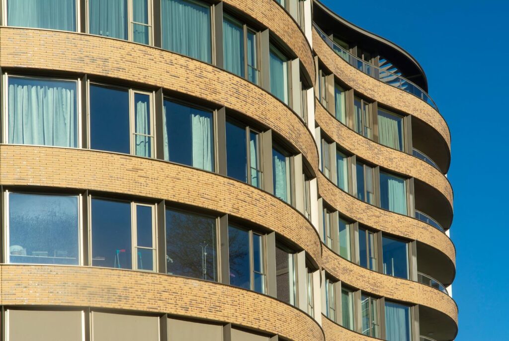 Gebouw met golvende bakstenen gevel en grote ramen, geen vliesgevelconstructie zichtbaar
