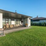 Moderne bungalow met overdekt terras, tuinmeubilair en strak onderhouden gazon in een groene woonwijk