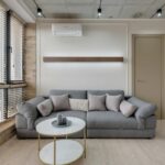 Moderne woonkamer met grijze bank en professioneel geplaatste airco bovenaan de muur voor optimaal comfort