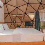 Sfeervolle slaapkamer met houten bed, airco en geometrisch koepelvormig plafond in een glamping accommodatie