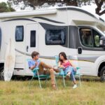 Stel met surfplanken bij camper plant